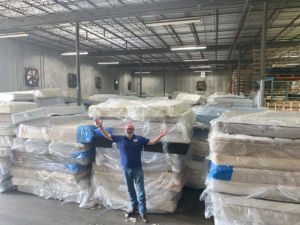 Board Chairman Hal Lynde stands in front of a mountain of mattresses for recycling